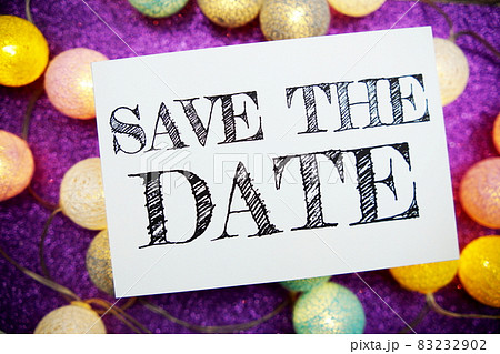 Save The Date text on paper card top view on purple bokeh background 83232902