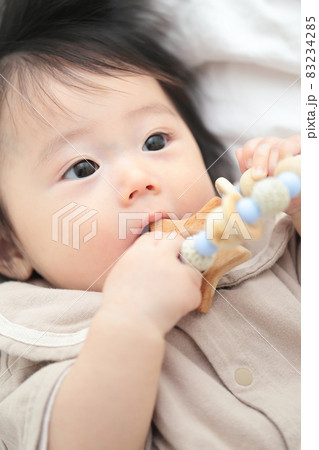 歯固めのおもちゃをかじる生後6ヶ月の赤ちゃんの女の子の写真素材