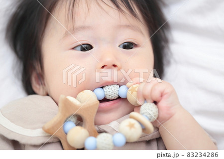 歯固めのおもちゃをかじる生後6ヶ月の赤ちゃんの女の子の写真素材