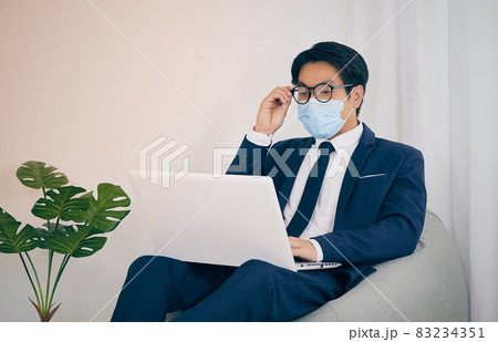 Asian Financial Advisor Wear Face Mask Hold Glasses Use Laptop in Vintage Tone Asian Financial Advisor Wear Face Mask Hold Glasses Use Laptop in Vintage Tone 83234351