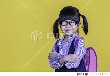 Portrait of young happy little cute asian girl in school uniform isolated on yellow background with copy space. Education for toddler or preschool, childhood lifestyle back to school concept 83237487