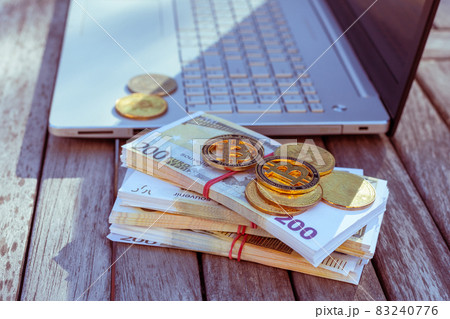 There is a laptop and bitcoins on the table. 83240776