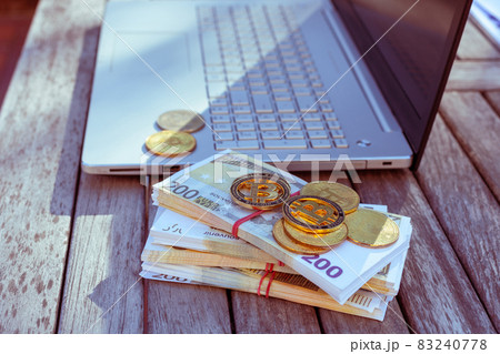 There is a laptop and bitcoins on the table. There is a laptop and bitcoins on the table. 83240778