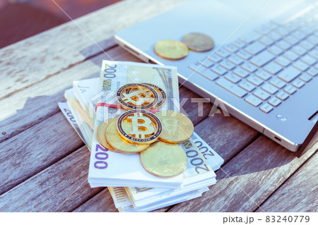There is a laptop and bitcoins on the table. There is a laptop and bitcoins on the table. 83240779