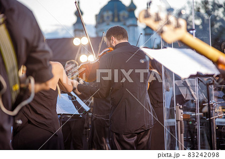 Male musician playing violin at outdoor concert 83242098