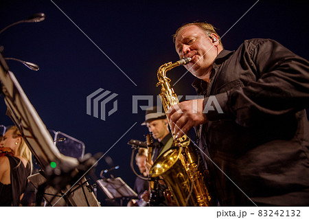 Male musician playing saxophone under blue night sky Male musician playing saxophone under blue night sky 83242132