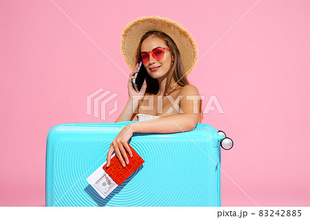 Glad girl with suitcase, tickets, money and passport are going to travel while speaking on phone  83242885