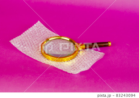 Magnifying glass and bubble wrap on pink background. 83243094