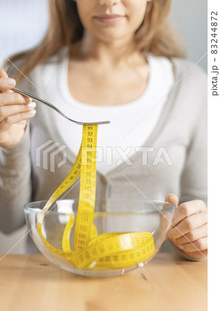 Young woman holding fork with measuring tapes. Young woman holding fork with measuring tapes. 83244872