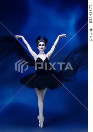 Portrait of young incredibly beautiful woman, ballerina in black ballet outfit, tutu dancing at blue studio full of light. Portrait of young incredibly beautiful woman, ballerina in black ballet outfit, tutu dancing at blue studio full of light. 83245379