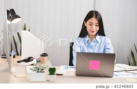 Asian woman working on a laptop with a cheerful and happy smile while working at the office 83246805