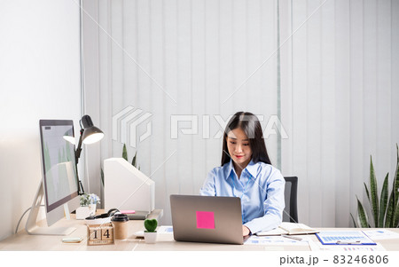 Asian woman working on a laptop with a cheerful and happy smile while working at the office 83246806