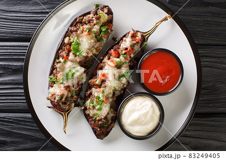 Berenjena Rellena Spanish Stuffed Eggplant with ground beef, vegetables and cheese close-up in a plate. Horizontal top view Berenjena Rellena Spanish Stuffed Eggplant with ground beef, vegetables and cheese close-up in a plate. Horizontal top view 83249405