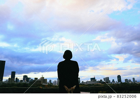 夕暮れ時の空と街を眺める女性のシルエット 83252006