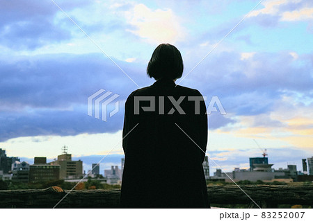 夕方の空と街並みを眺める女性のシルエット 83252007