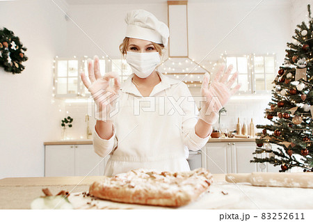 a cheerful chef prepares a Christmas cake. Lady cook in a cute apron breaking an egg into flour to make cake. The process of cooking. Step by step. Unsurpassed pre-holiday atmosphere and home comfort a cheerful chef prepares a Christmas cake. Lady cook in a cute apron breaking an egg into flour to make cake. The process of cooking. Step by step. Unsurpassed pre-holiday atmosphere and home comfort 83252611