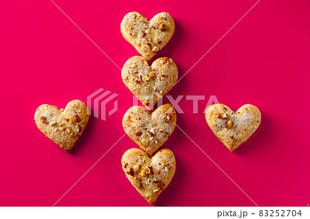 Heart shaped cookies for valentines day on pink background. Composition of almond cookies in the shape of a heart on a pink background Heart shaped cookies for valentines day on pink background. Composition of almond cookies in the shape of a heart on a pink background 83252704