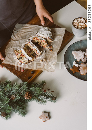 Woman serves Christmas pastries, stollen on a wooden board. Woman serves Christmas pastries, stollen on a wooden board. 83253298