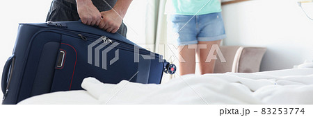 Man lifting heavy suitcase in front of woman in hotel room closeup Man lifting heavy suitcase in front of woman in hotel room closeup 83253774