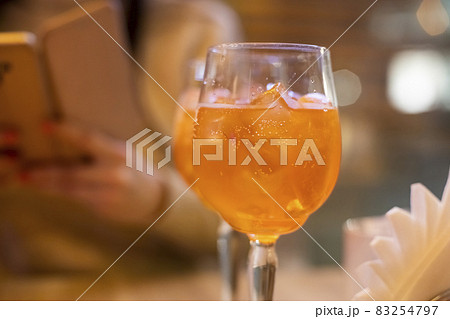 Two glasses of wine with spritz stand on a wooden table in a cafe, in the rays of the setting sun. Italian alcoholic drink with oranges and ice. Close-up, selective focus, 83254797