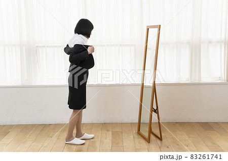 姿見の前でジャケットを着る女性 83261741