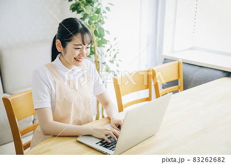 パソコンを使うエプロン姿の女性(笑顔) パソコンを使うエプロン姿の女性(笑顔) 83262682