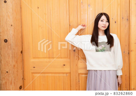 木の扉の前でポージングをしている若い日本人女性 83262860