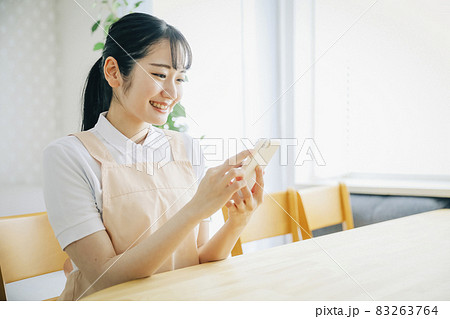 スマホを使うエプロン姿の女性 83263764
