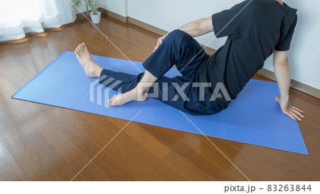 自宅でヨガ・ストレッチする男性。中臀筋のストレッチ。ねじりのポーズ。 83263844