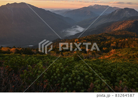 日の出で赤く染まる山肌を穂高連峰から見る 83264587
