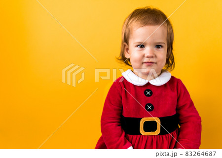 Banner Portraite Cute Happy Cheerful Chubby Baby Girl in Santa Suit Looking On Camera At Yellow Background. Child Play Christmas Scene Celebrating Birthday. Kid Have Fun Spend New Year Time Copy Space Banner Portraite Cute Happy Cheerful Chubby Baby Girl in Santa Suit Looking On Camera At Yellow Background. Child Play Christmas Scene Celebrating Birthday. Kid Have Fun Spend New Year Time Copy Space 83264687