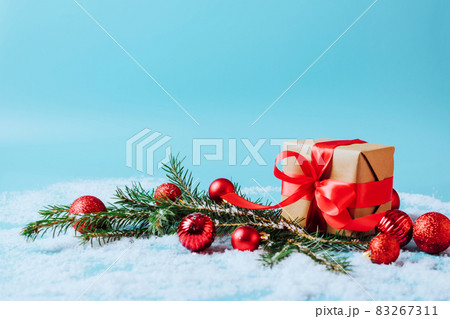 Festive box with a red bow on a blue background with Christmas toys balls branch of fluffy spruce sparkles and confetti . New Year Christmas concept. Flat festive mockup with copy space 83267311