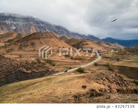 Scenic winding road in red valley. Dramatic view of winding road in high mountain pass. Dagestan. Scenic winding road in red valley. Dramatic view of winding road in high mountain pass. Dagestan. 83267539