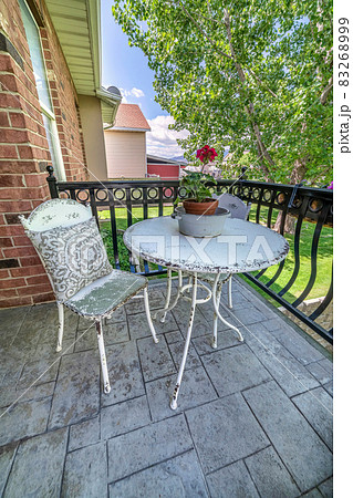 Metal round table and chairs with flowers and pillow at the balcony of a house Metal round table and chairs with flowers and pillow at the balcony of a house 83268999