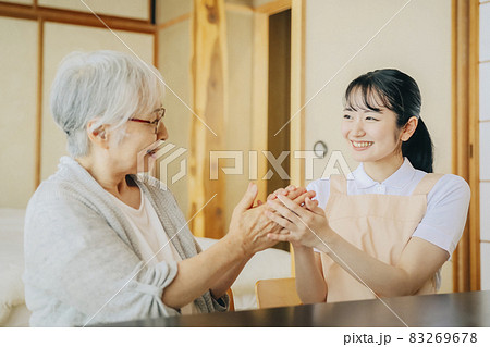 高齢者女性と話す女性スタッフ 83269678