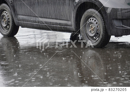 雨をはじくアスファルトの地面と駐車された車 83270205