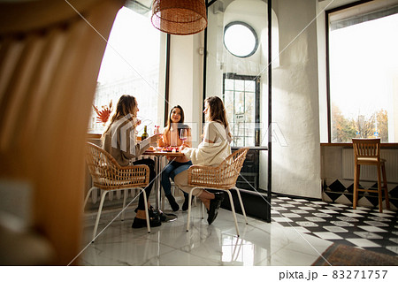Portrait of three beautiful women spending time together, having lunch with wine on warm sunny day 83271757
