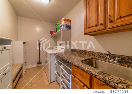 Laundry room of home with sink washing machine dryer cabinets and storage bins 83274153