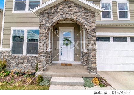 Beautiful facade of home with arched stone entrance and glass paned front door 83274212