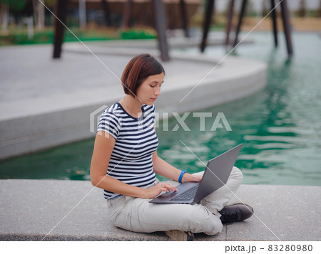 female student working with laptop in campus park. 83280980