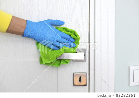 Woman cleaning a door handle with a disinfectant rag 83282361