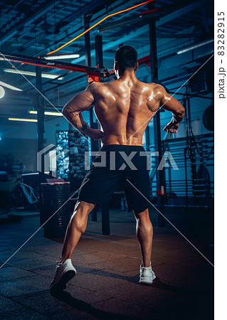Portrait of young man, muscled athlete, bodybuilder posing at sport gym, indoors. Concept of sport, activity, healthy lifestyle 83282915