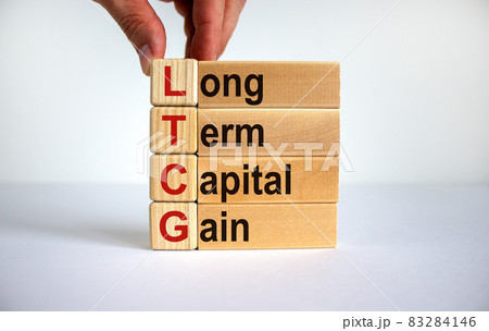 LTCG symbol. Wooden cubes and blocks with words 'LTCG - long term capital gain'. Beautiful white background. Businessman hand. Business and LTCG concept. Copy space. LTCG symbol. Wooden cubes and blocks with words 'LTCG - long term capital gain'. Beautiful white background. Businessman hand. Business and LTCG concept. Copy space. 83284146
