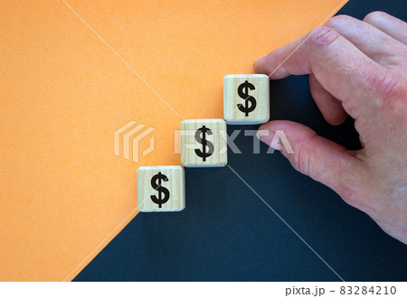 Business concept growth success process. Wood blocks with dollar sign stacking as step stair on paper peach and black background, copy space. Male hand. 83284210