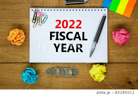 2022 fiscal new year symbol. White note, words 2022 fiscal year on beautiful wooden table, colored paper, colored pencils, paper clips, coins. Business and 2022 fiscal new year concept. 2022 fiscal new year symbol. White note, words 2022 fiscal year on beautiful wooden table, colored paper, colored pencils, paper clips, coins. Business and 2022 fiscal new year concept. 83285011