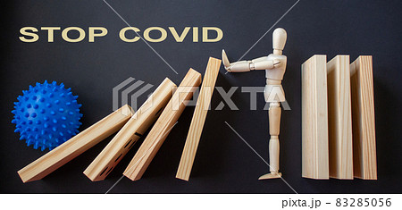 COVID-19 Pandemic Coronavirus concept. Wooden model of man stopping wooden domino blocks. Inscription covid19. 83285056