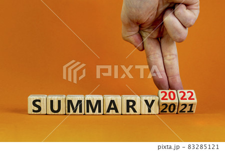 Symbol of planning 2022 summary new year. Businessman turns a wooden cube and changes words 'summary 2021' to 'summary 2022'. Beautiful orange background, copy space. Business, 2022 summary concept. 83285121