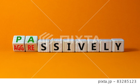 Passively or aggressively symbol. Turned wooden cubes and changed the word passively to aggressively. Psychological and passively or aggressively concept. Beautiful orange background, copy space. 83285123