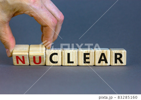 Nuclear or clear symbol. Businessman turns a cube and changes the word 'nuclear' to 'clear'. Beautiful grey background. Nuclear or clear and business concept. Copy space. Nuclear or clear symbol. Businessman turns a cube and changes the word 'nuclear' to 'clear'. Beautiful grey background. Nuclear or clear and business concept. Copy space. 83285160
