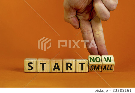 Start small and now symbol. Businessman turns wooden cubes and changes words 'start small' to 'start now'. Beautiful orange background, copy space. Business and start small and now concept. 83285161